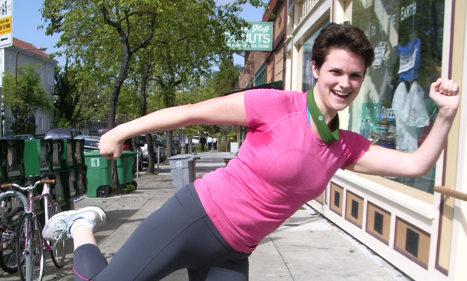 a young woman dressed in pink and gray running clothes warms up on a street corner. Photo by Barbara Newhall