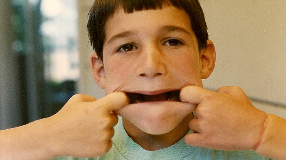 A 7-year-old boy makes a face by stretching his mouth wide. Photo by Barbara Newhall