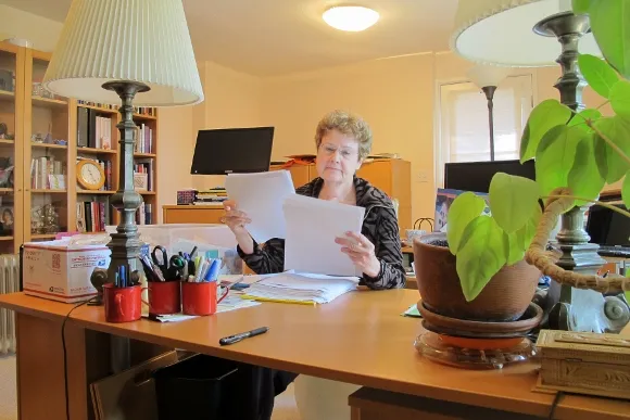 Barbara Falconer Newhall in her San Francisco Bay Area writing room with desk and bookcases editing the paper print-out of her book manuscript, "Wrestling with God." Photo by Barbara Newhall