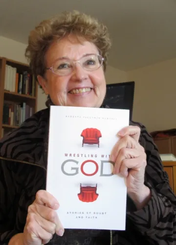 Experiencing the shame of aging, author Barbara Falconer Newhall uses a copy of her book Wrestling with God, to cover her droopy chin as she approaches the Big Seven-Five. Photo by Barbara Newhall