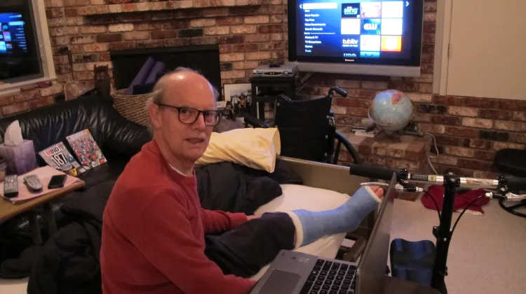 A 75-year-old man with his broken ankle in a cast in a hospital bed in his den with TV. Photo by Barbara Newhall