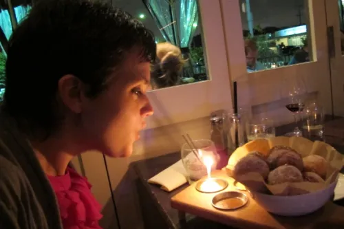 Pretty young woman blows out a birthday candle with her donut dessert at Waterloo & City in Culver City. Photo by BF Newhall