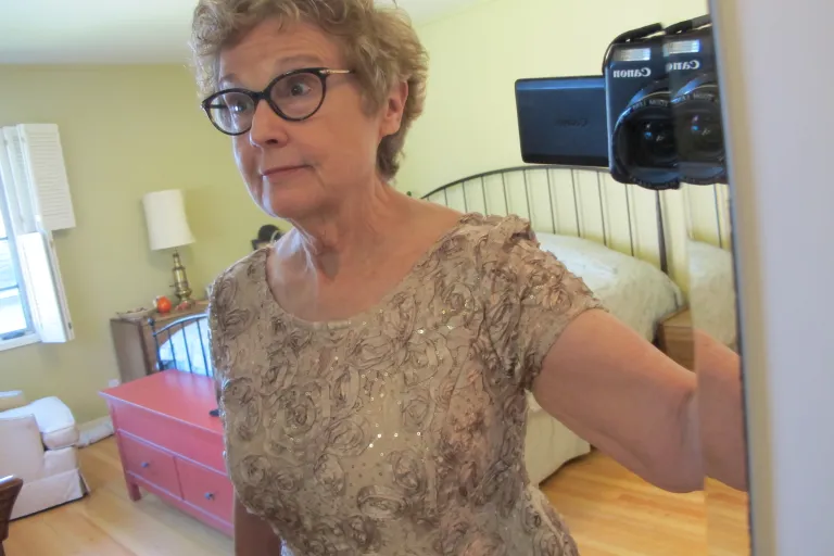 A mother of the bride tries on dresses to cover the figure flaws she'll take to her daughter's wedding -- flabby arms, wobbly neck and falling bustline. Photo by Barbara Newhall
