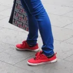 A Shanghai woman wears bright red canvas sneakers and tight blue slacks with blue and red tote bag. Photo by BF Newhall