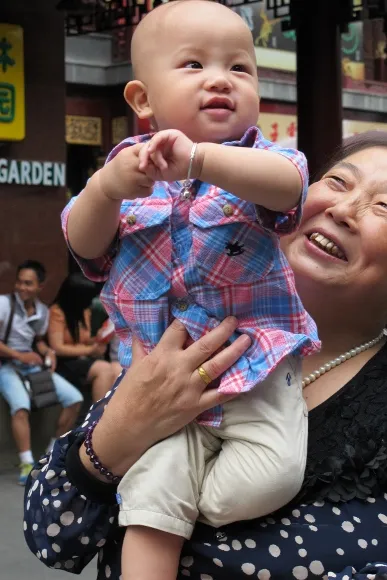 In Shanghai's Old Town, a proudly smiling grandmother holds up her grandson. Photo by BF Newhall