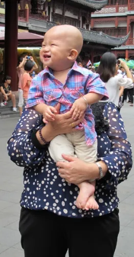 A baby in Shanghai smiles and looks towards his mother who is taking a photo of him. Photo by BF Newhall