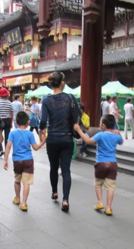Twin boys in Shanghai dressed in identical shorts and blue shirts with apparent mother. Photo by BF Newhall