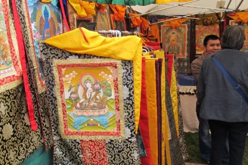 Kathmandu artist in his stall at Himalayan Fair Berkeley 2014 with dozens of thangkas from Nepal. Photo by BF Newhall