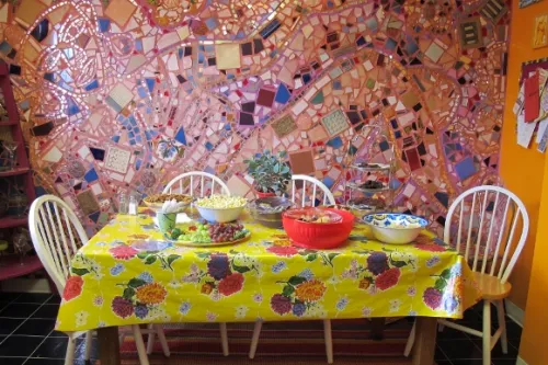 jingletown-art-studio Food is served at Jingletown Art Studio on a table with flowered oilcloth tablecloth before a pink mosaic wall. Photo by BF Newhall