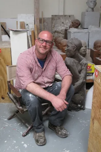 Christopher-Kanyusik Christopher Kanyusik in his Oakland sculpture studio with his ceramic figures in background. Photo by BF Newhall