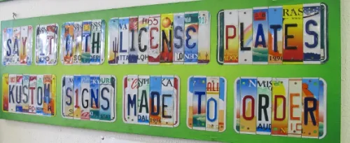 Bill-Silveira-license Bill Silveira cut up US license plates to make a sign reading "Kustom Signs Made to Order. Photo by BF Newhall". Photo by BF Newhall