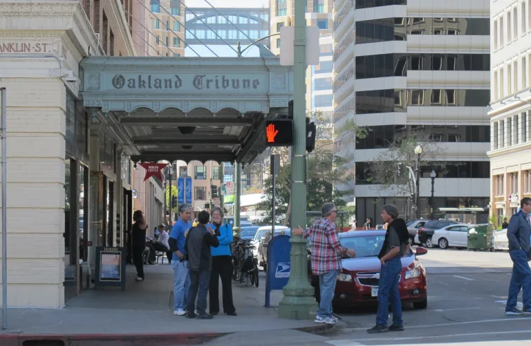 Former employees gathered under facade overhang of Oakland, CA, Tribune bldg. On April 4, 2016, former employees of the Oakland, California, Tribune, had a wake in honor of the paper's last day of publication. Photos by Barbara Newhall