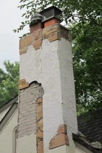 The stucco has fallen away from the chimney on a Tudor bungalow in Minneapolis, revealing the brick work underneath. Photo by Barbara Newhall