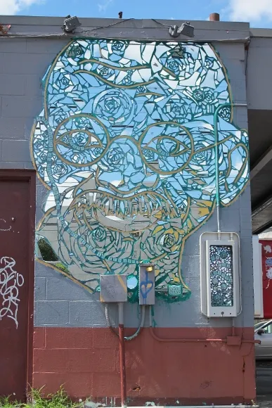 The face of Mahatma Gandhi reproduced with pieces of mirror on the wall of a check cashing establishment reflects a blue sky in East Austin, TX. Photo by BF Newhall