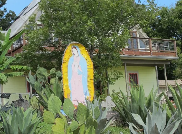 A sun-faded image of the virgin of guadalupe stands in an austin, tx, front yard next to a plaque honoring a soldier son who died in the Korean War. Photo by BF Newhall