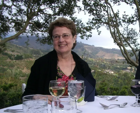 A 67-year-old woman enjoys herself at a white table cloth dinner with wine and a rural setting. BF Newhall photo