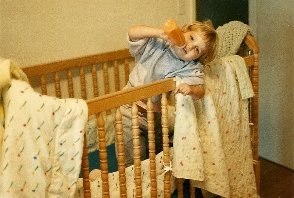 toddler-enjoying-her-bottle-in-her-crib Two-year-old girl enjoys her bottle in her crib with blankies. Photo by BF Newhall