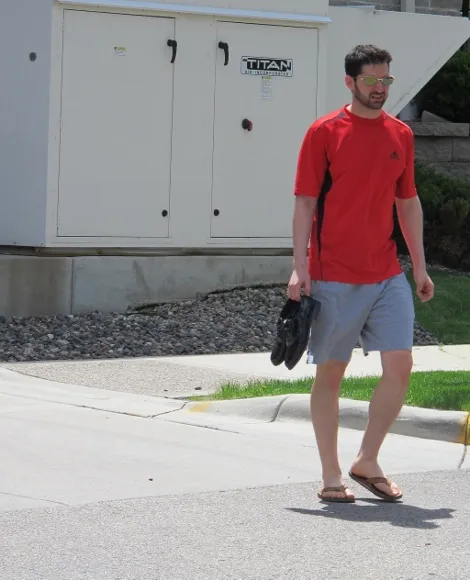A bridegroom wearing shorts and T-shirt on the day before his wedding carries his patent leather wedding shoes. Photo by BF Newhall