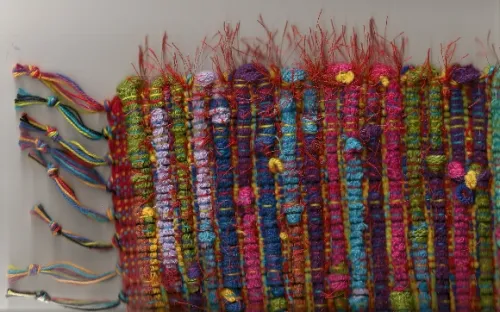 Deatil of a rug woven by Mary Helen Blohm showing woof made of socks and eyelash yarn embellishment. Photo by BF Newhall