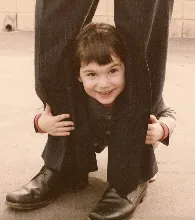A boy peers through his father's legs. Photo by BF Newhall