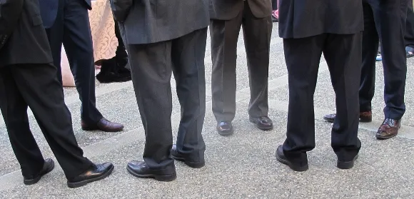 A crowd of men, all wearing practical, low-heeled oxford shoes -- ready for action and definitely not feminine. Photo by Barbara Newhall